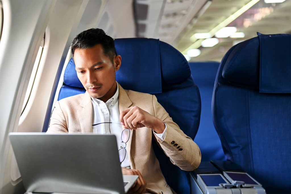 man using laptop on airplane