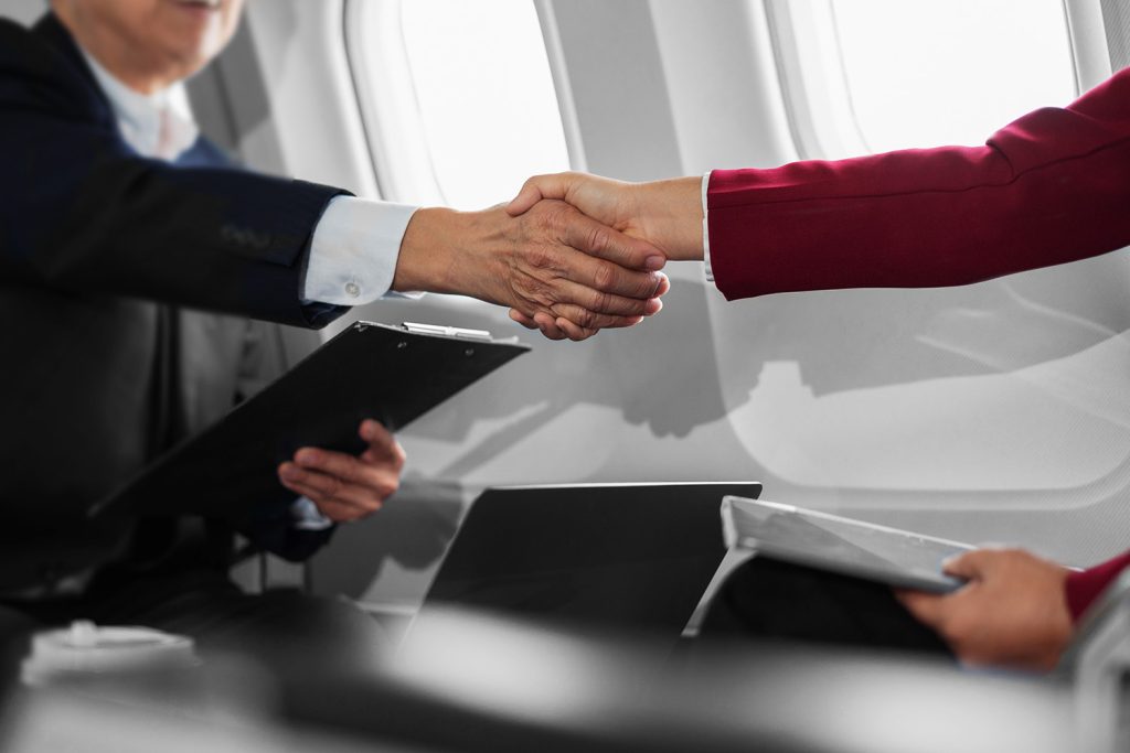 business people shaking hands on airplane