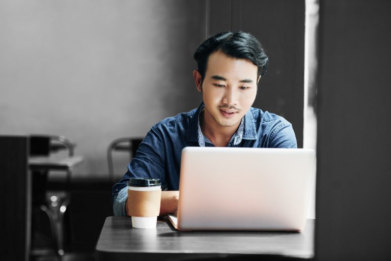 man working on laptop in coffee shop