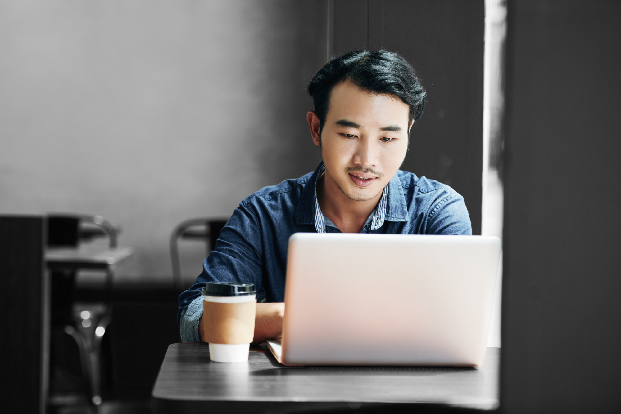 man working on laptop in coffee shop
